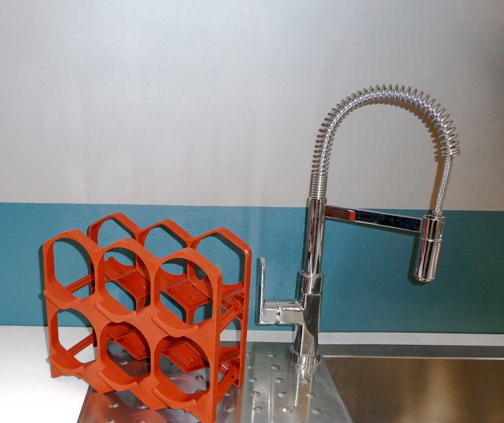 Le casier à bouteilles rouge brique de drinkcase ne prend pas de place sur le rebord d'un plan de travail d'une cuisine